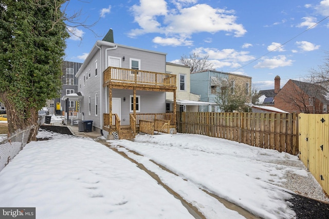 snow covered house featuring a wooden deck