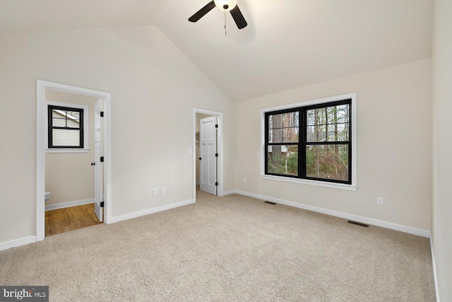 unfurnished bedroom with vaulted ceiling, ceiling fan, light colored carpet, and multiple windows