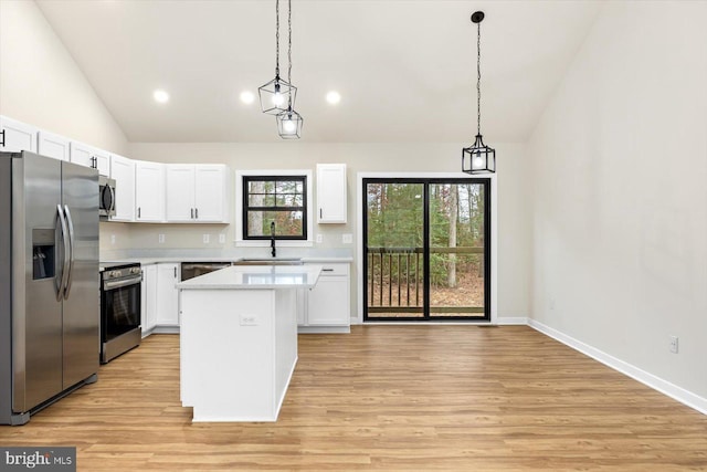 kitchen with decorative light fixtures, sink, appliances with stainless steel finishes, and a center island