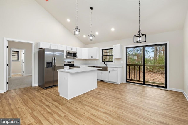 kitchen with appliances with stainless steel finishes, pendant lighting, a kitchen island, and high vaulted ceiling