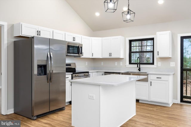 kitchen featuring light hardwood / wood-style floors, stainless steel appliances, decorative light fixtures, a kitchen island, and white cabinets