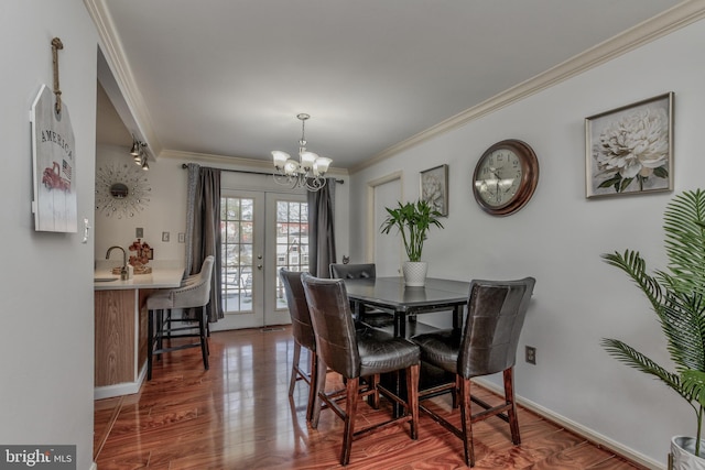 dining space featuring wood-type flooring, ornamental molding, french doors, and an inviting chandelier