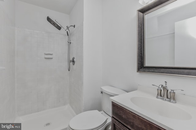 bathroom featuring toilet, vanity, and a tile shower