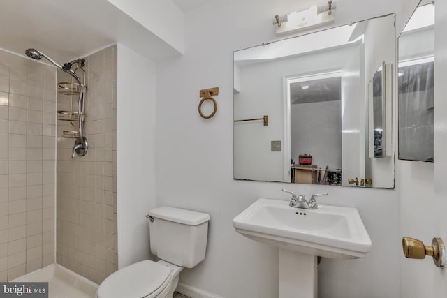 bathroom with sink, toilet, and a tile shower