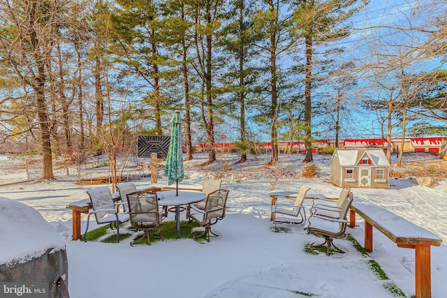 snow covered patio featuring a trampoline and an outdoor structure