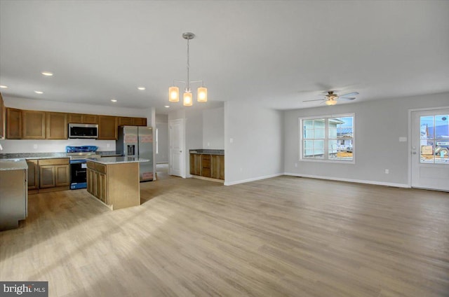 kitchen with a wealth of natural light, pendant lighting, a center island, and stainless steel appliances