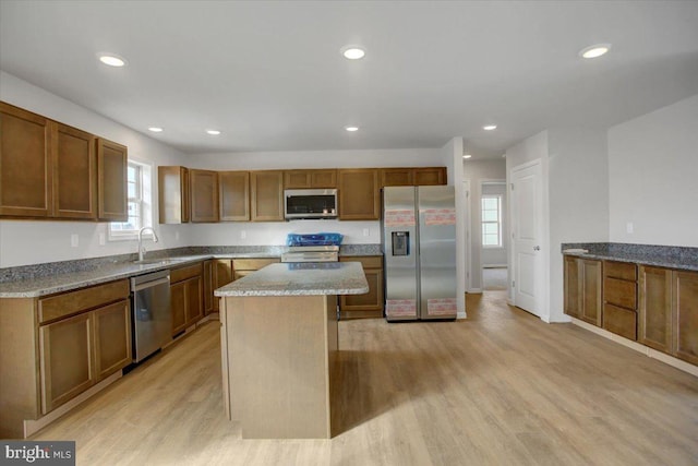 kitchen featuring light hardwood / wood-style floors, sink, appliances with stainless steel finishes, and a center island