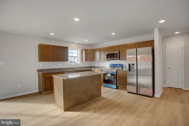 kitchen featuring light hardwood / wood-style floors, a kitchen island, sink, appliances with stainless steel finishes, and light stone counters