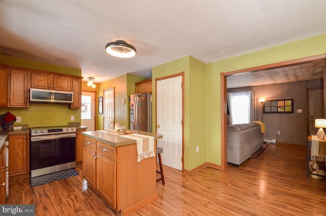 kitchen featuring a healthy amount of sunlight, a kitchen bar, stainless steel appliances, and a kitchen island