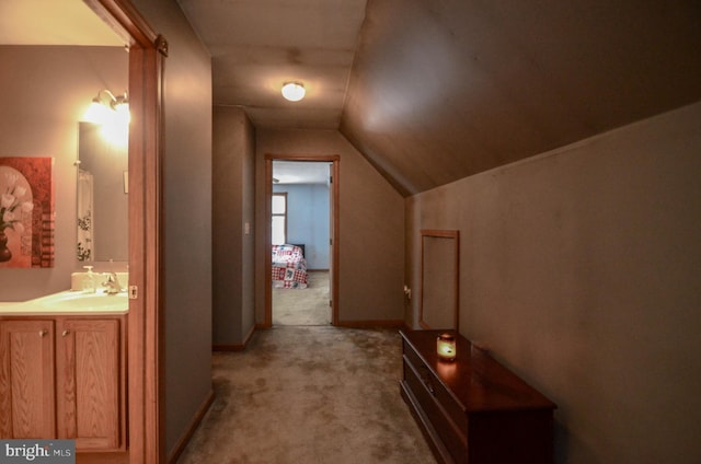 hall with vaulted ceiling, carpet, and sink