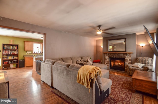 living room with ceiling fan, wood-type flooring, and a fireplace