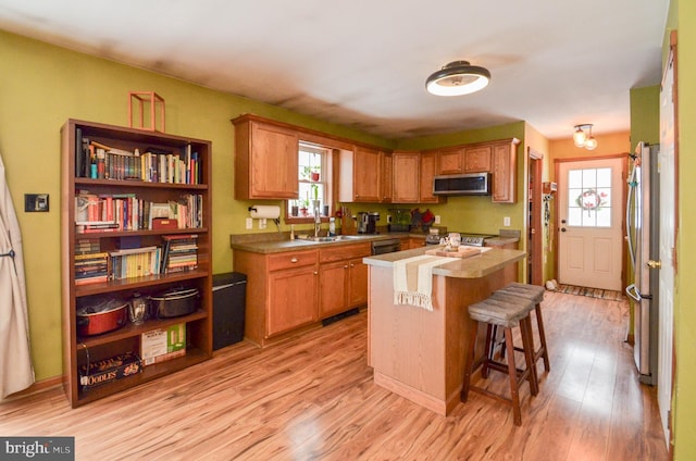 kitchen featuring light hardwood / wood-style floors, a center island, a healthy amount of sunlight, appliances with stainless steel finishes, and a breakfast bar area