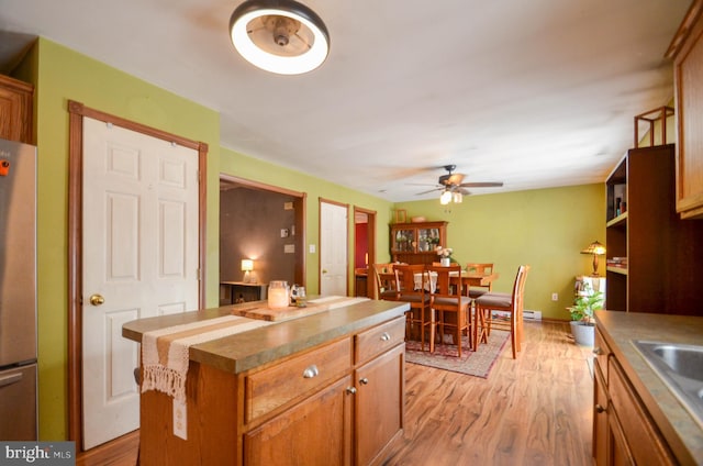 kitchen featuring ceiling fan, refrigerator, a center island, sink, and light hardwood / wood-style flooring