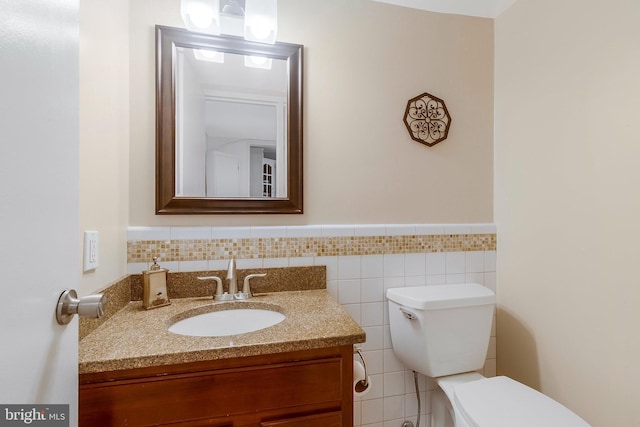 bathroom featuring tile walls, toilet, and vanity