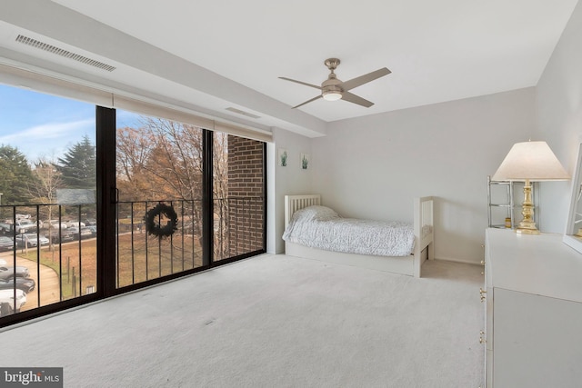 carpeted bedroom with ceiling fan, a wall of windows, and multiple windows