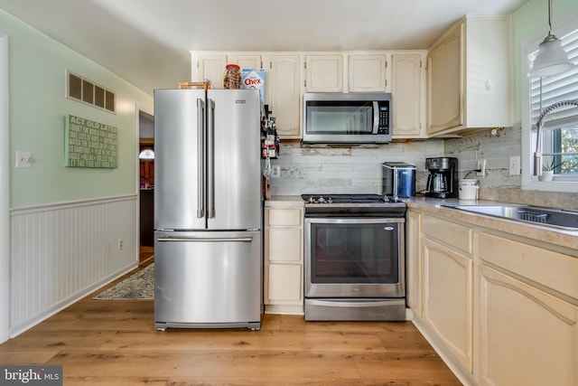 kitchen featuring decorative light fixtures, sink, light hardwood / wood-style flooring, and stainless steel appliances