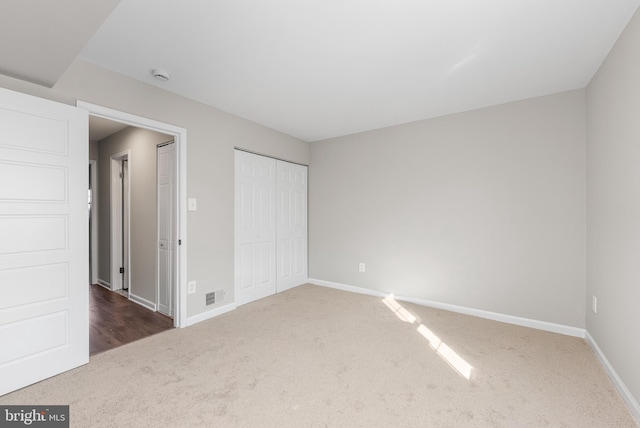 unfurnished bedroom featuring dark carpet and a closet