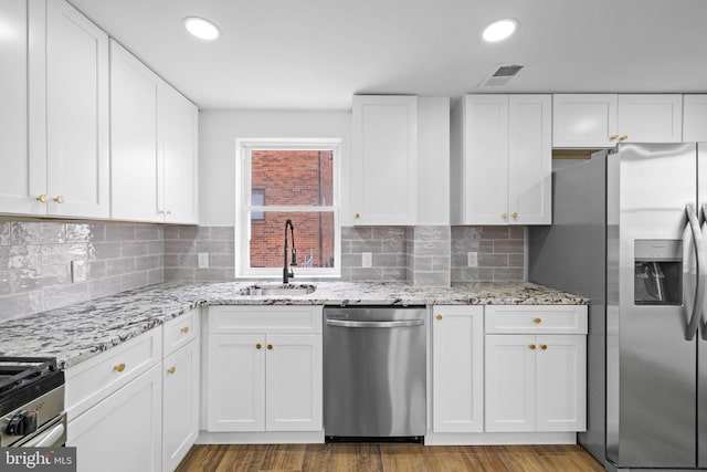 kitchen with appliances with stainless steel finishes, white cabinets, tasteful backsplash, and sink