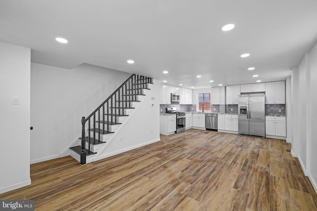 kitchen featuring wood-type flooring, white cabinetry, stainless steel appliances, tasteful backsplash, and sink