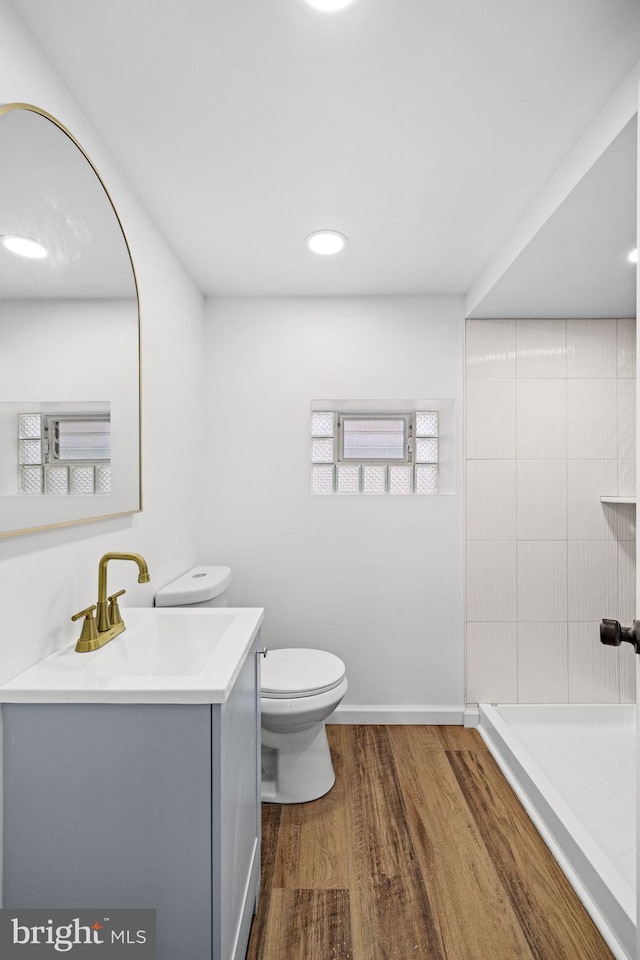 bathroom featuring vanity, toilet, hardwood / wood-style floors, and tiled shower