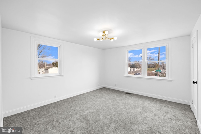 carpeted empty room with a notable chandelier