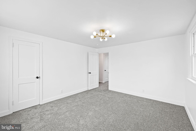 unfurnished room featuring carpet floors and a chandelier