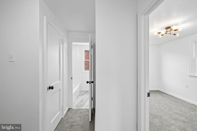 hallway with carpet floors and a notable chandelier