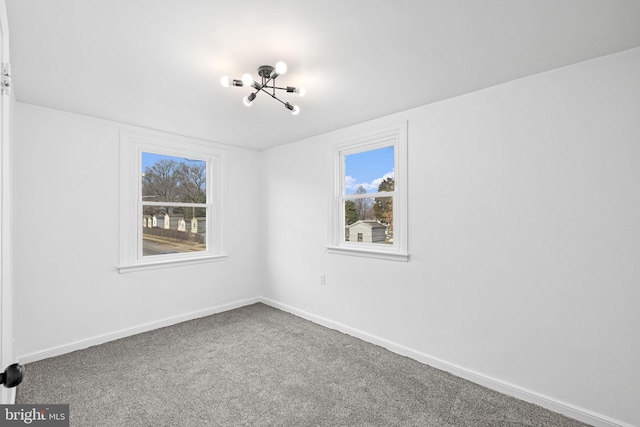 carpeted empty room featuring a chandelier