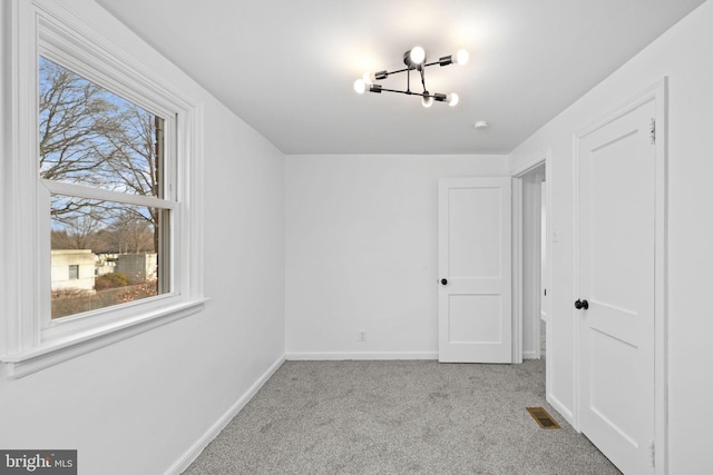 interior space featuring plenty of natural light, light carpet, and an inviting chandelier