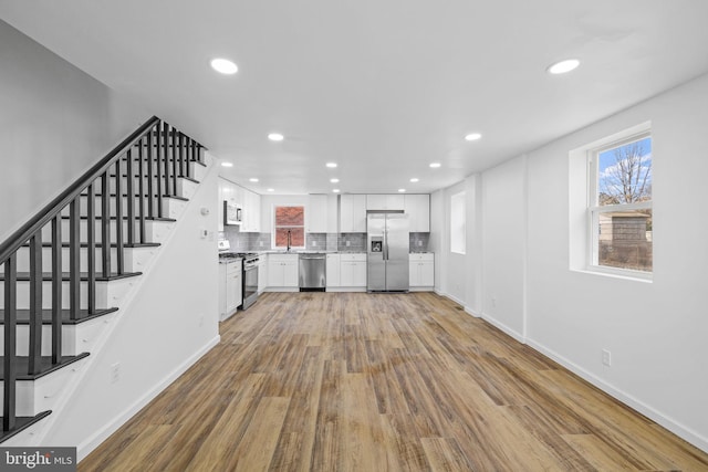 kitchen featuring hardwood / wood-style floors, white cabinets, stainless steel appliances, tasteful backsplash, and sink