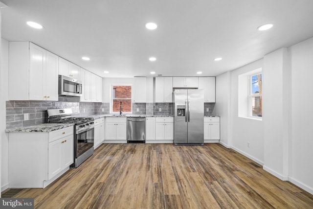 kitchen with white cabinetry, stainless steel appliances, tasteful backsplash, dark hardwood / wood-style flooring, and sink