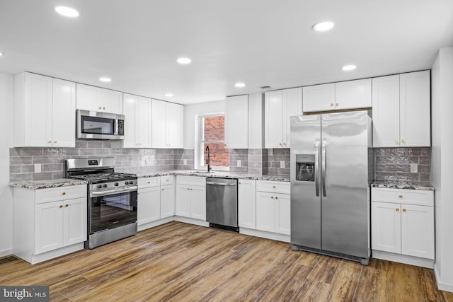 kitchen with dark hardwood / wood-style floors, appliances with stainless steel finishes, white cabinets, and light stone counters