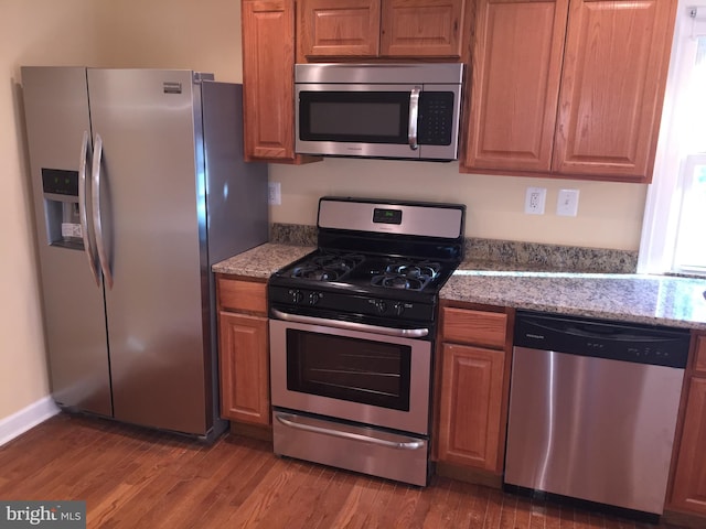 kitchen featuring dark wood-type flooring, light stone countertops, and stainless steel appliances