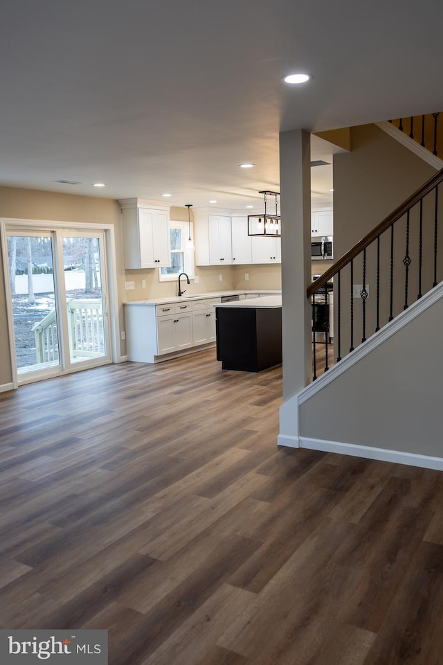 kitchen featuring sink, hanging light fixtures, dark wood-type flooring, white cabinets, and a chandelier