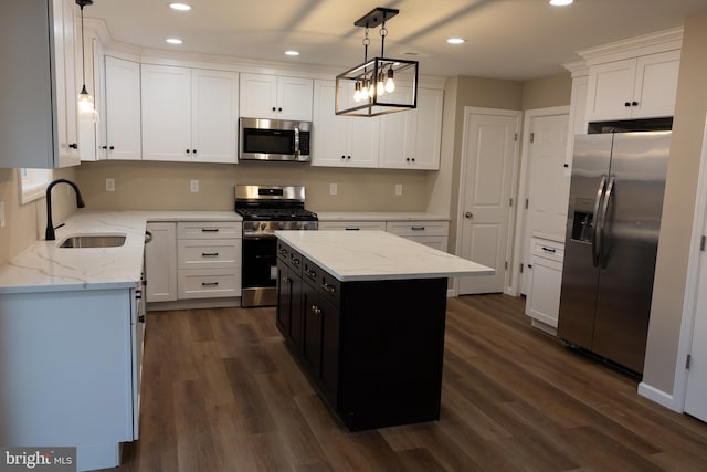 kitchen with white cabinets, a kitchen island, stainless steel appliances, sink, and hanging light fixtures