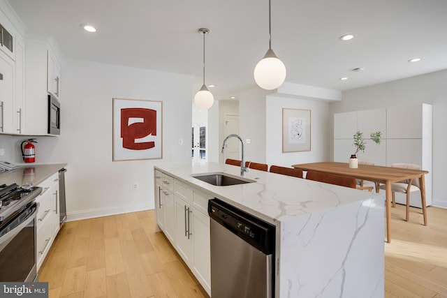 kitchen with white cabinetry, sink, stainless steel appliances, and a kitchen island with sink