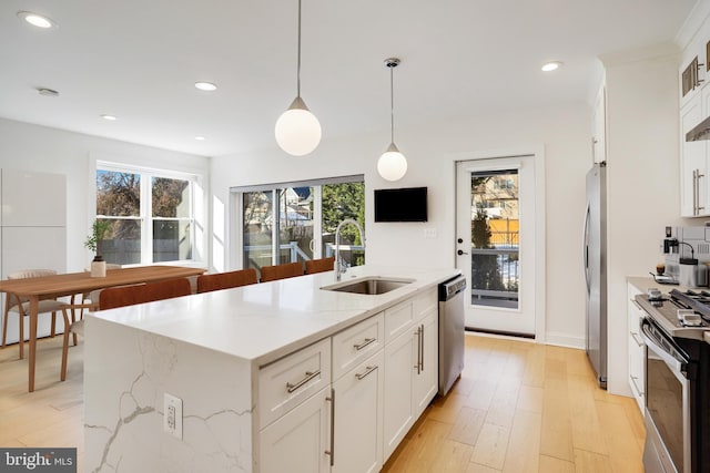 kitchen with sink, a kitchen island with sink, white cabinetry, and stainless steel appliances