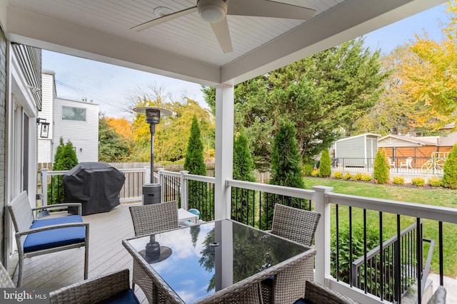 wooden deck with ceiling fan, a grill, and a lawn