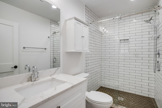 bathroom featuring toilet, vanity, and tiled shower