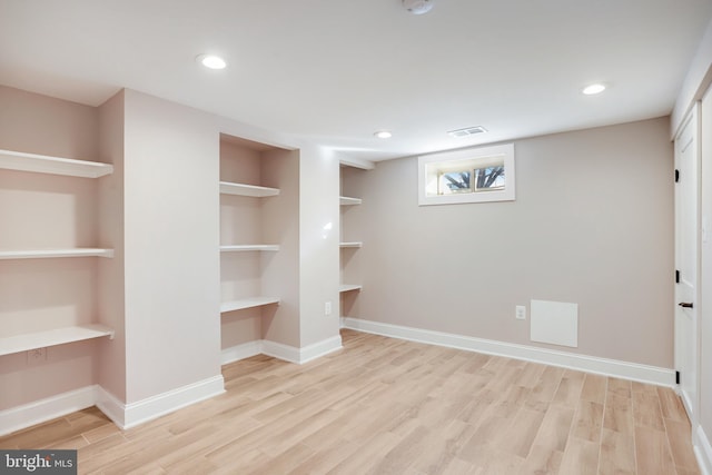 basement featuring light wood-type flooring, built in desk, and built in features