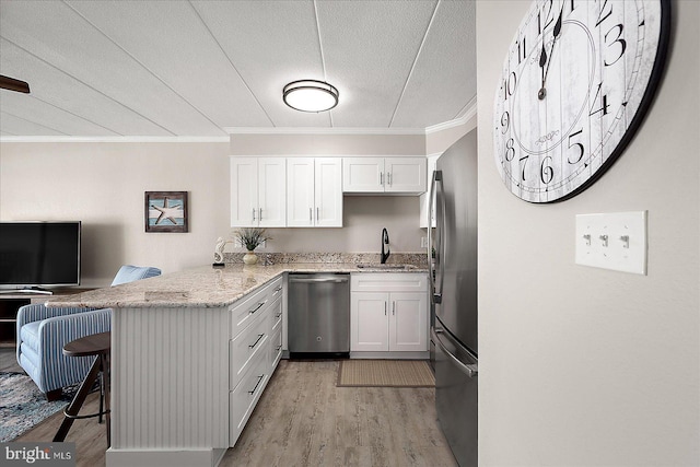 kitchen with white cabinetry, a breakfast bar area, kitchen peninsula, and appliances with stainless steel finishes