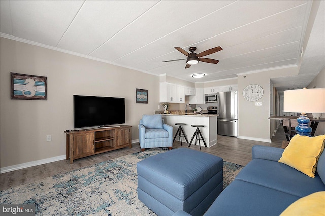 living room featuring hardwood / wood-style flooring, ceiling fan, ornamental molding, and sink