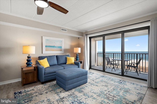 living room with hardwood / wood-style floors, ceiling fan, and a water view