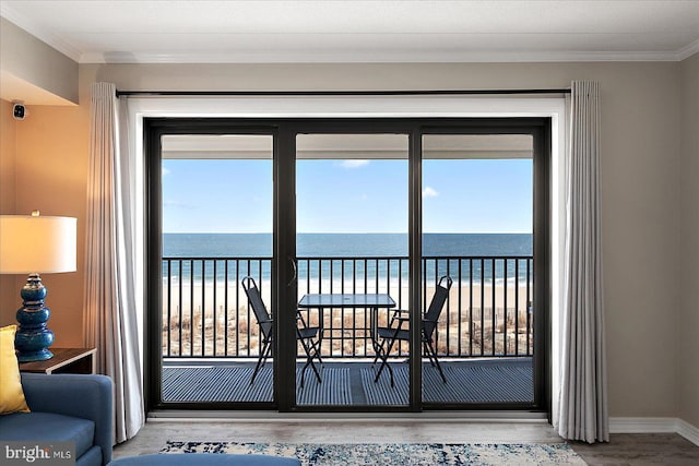 doorway to outside with a water view, ornamental molding, a view of the beach, and hardwood / wood-style flooring