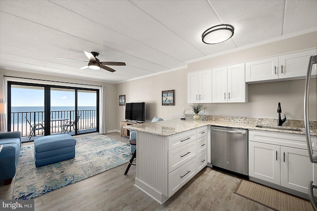 kitchen featuring sink, a water view, white cabinets, stainless steel dishwasher, and kitchen peninsula