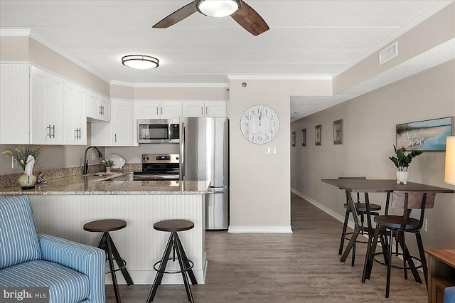 kitchen featuring sink, white cabinetry, appliances with stainless steel finishes, dark hardwood / wood-style flooring, and kitchen peninsula