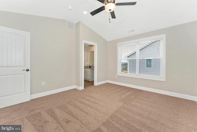 unfurnished bedroom with vaulted ceiling, ceiling fan, carpet flooring, and ensuite bath