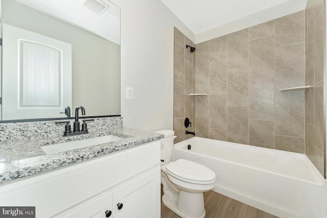 full bathroom featuring toilet, tiled shower / bath combo, wood-type flooring, and vanity