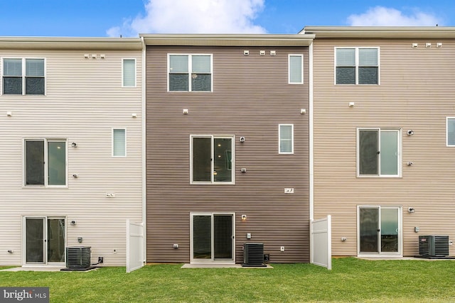 back of property featuring central AC unit and a yard