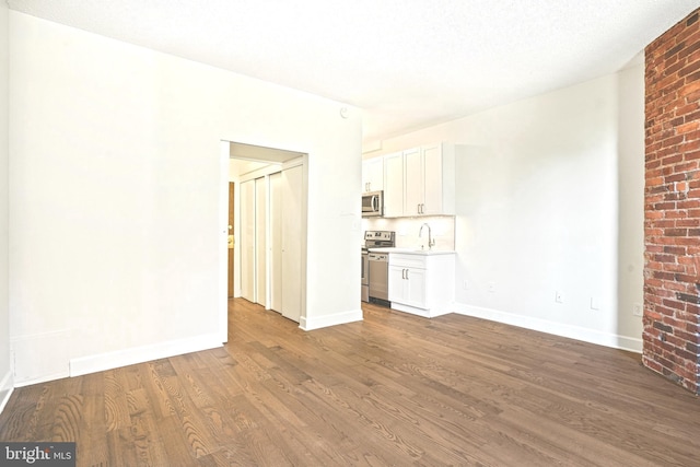 unfurnished living room featuring hardwood / wood-style floors and sink